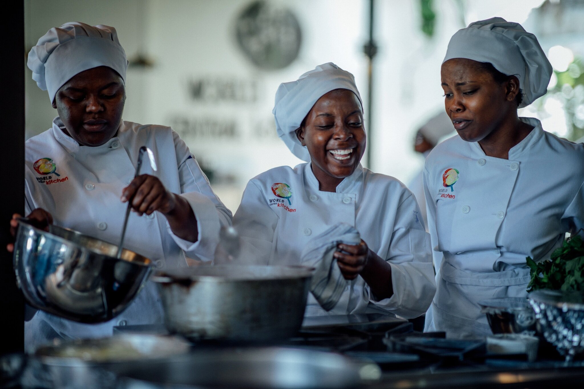 3 women in chefs coats cooking in a kitchen